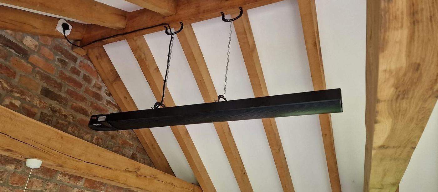 Infrared heater hung from oak beams in a barn conversion